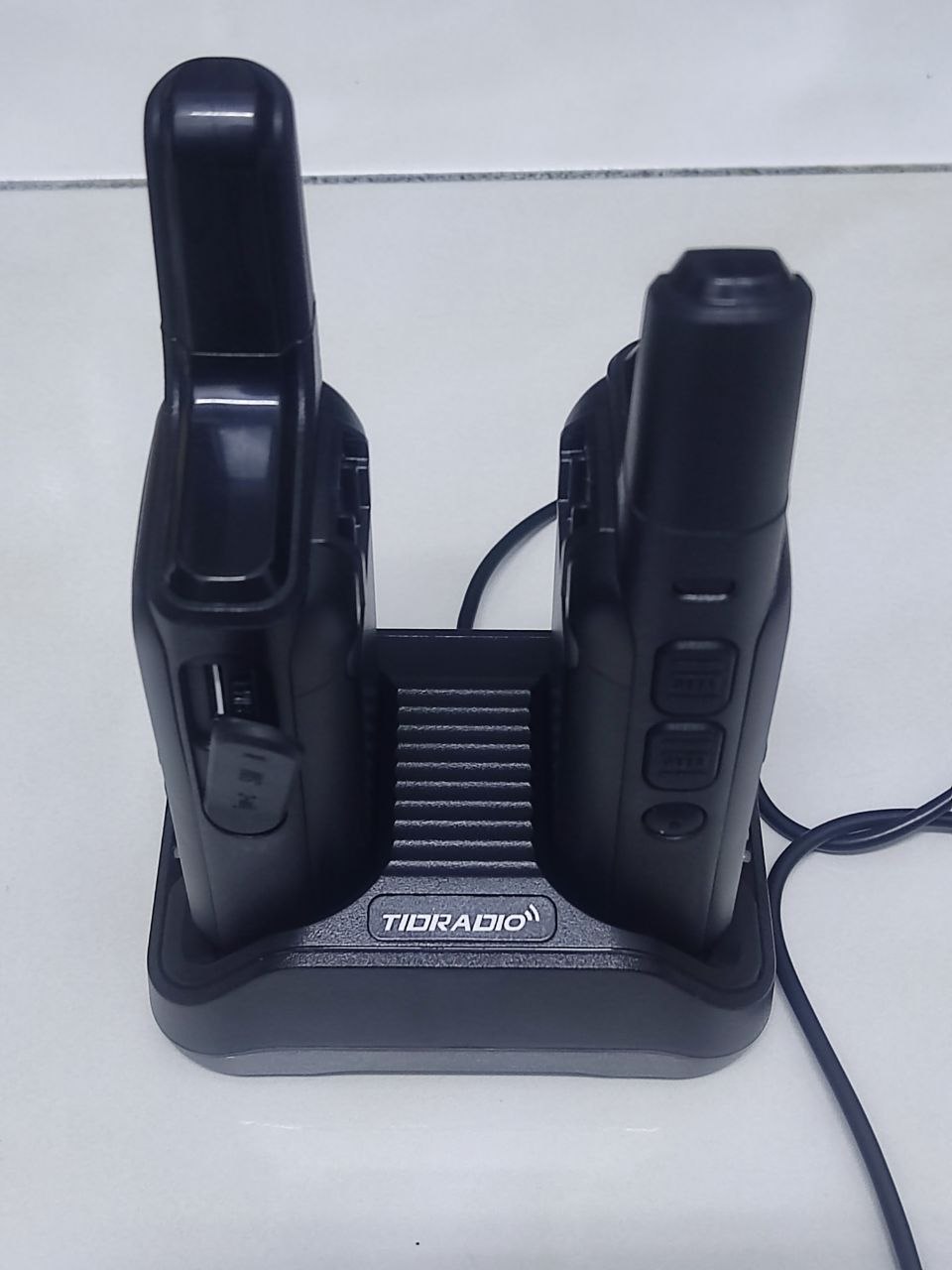 TIDRADIO TD-M2 Pro dual radios docked in desktop charging base showing side controls